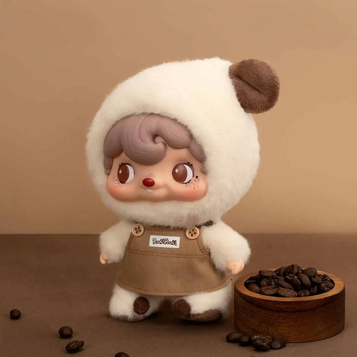 Pouka Pouka Coffee Time figure in fluffy white onesie and canvas apron next to a wooden bowl of coffee beans