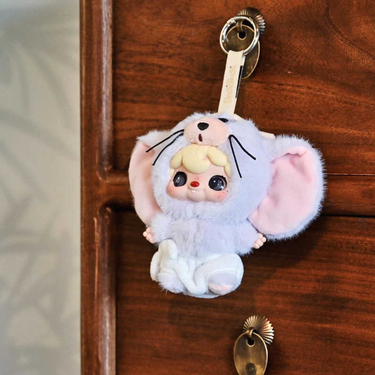 POUKAPOUKA gray Tom costume plush keychain hanging from a wooden drawer knob