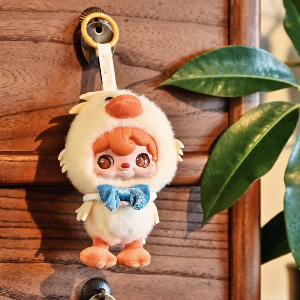 POUKAPOUKA Quacker duck costume plush keychain hanging beside a houseplant