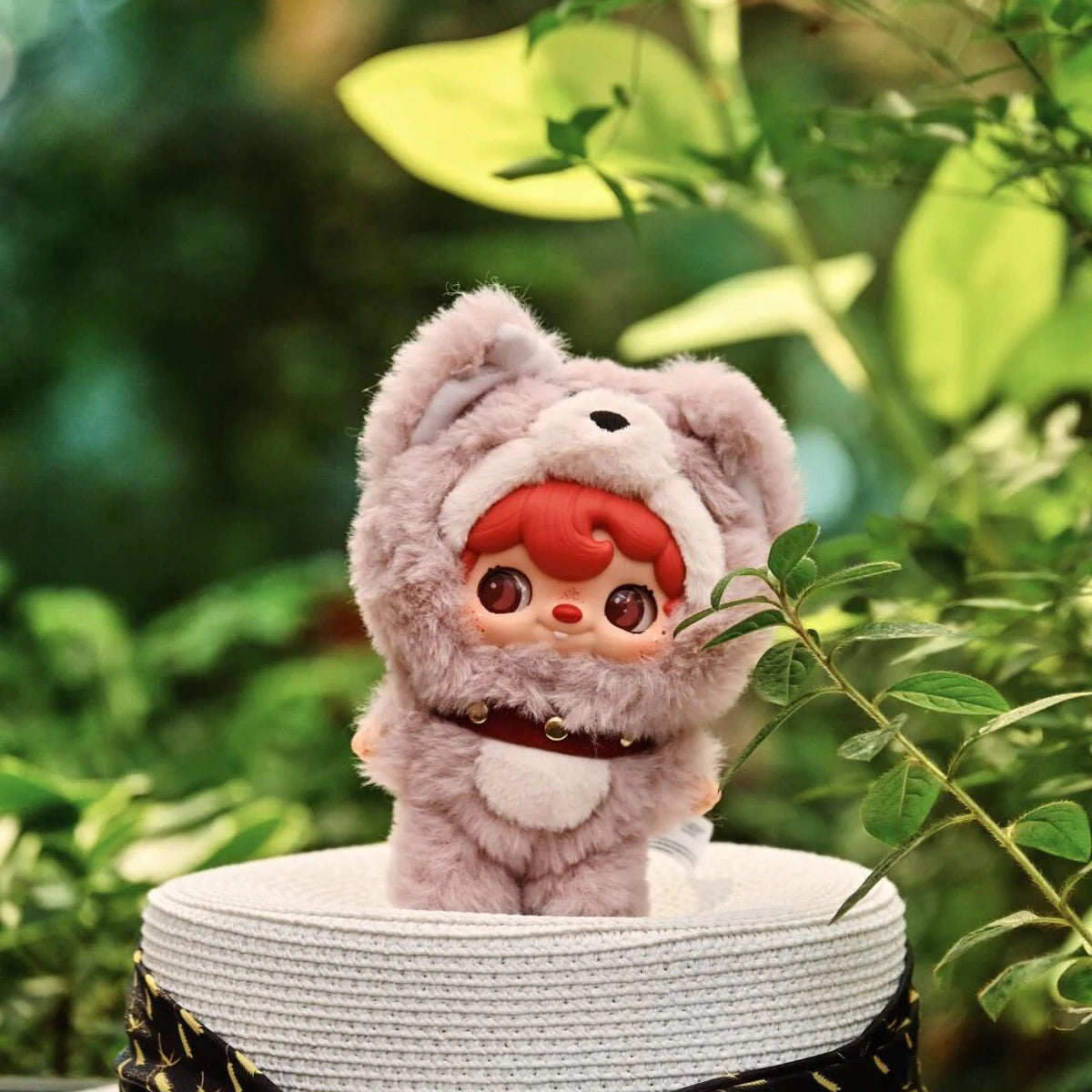 POUKAPOUKA in a lavender Tom costume displayed among green leaves