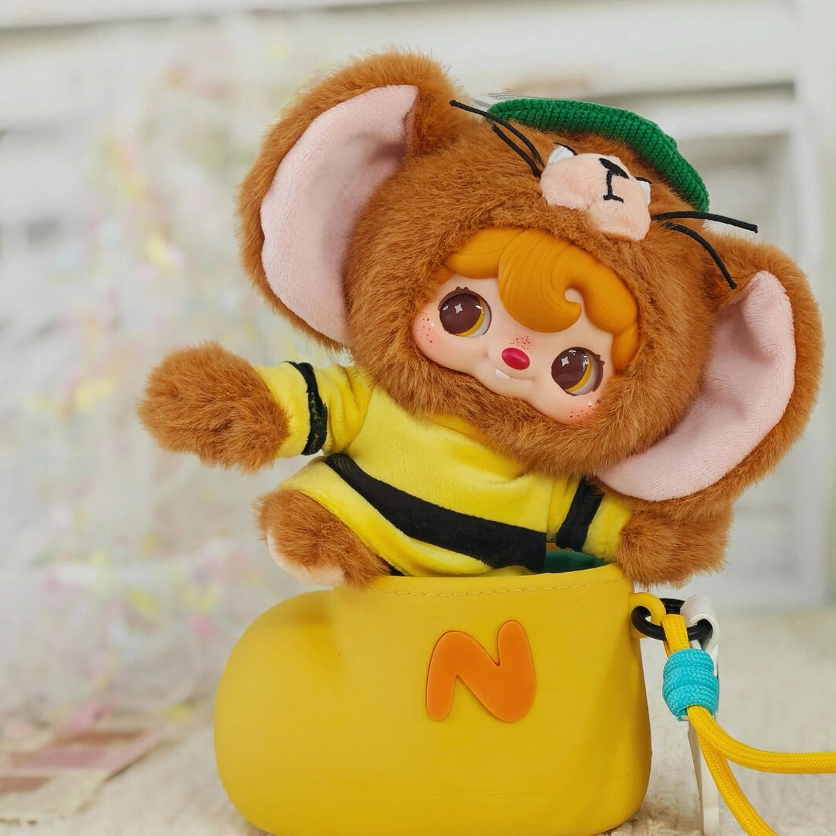 Secret POUKAPOUKA Jerry costume perched on a yellow bag with letter N