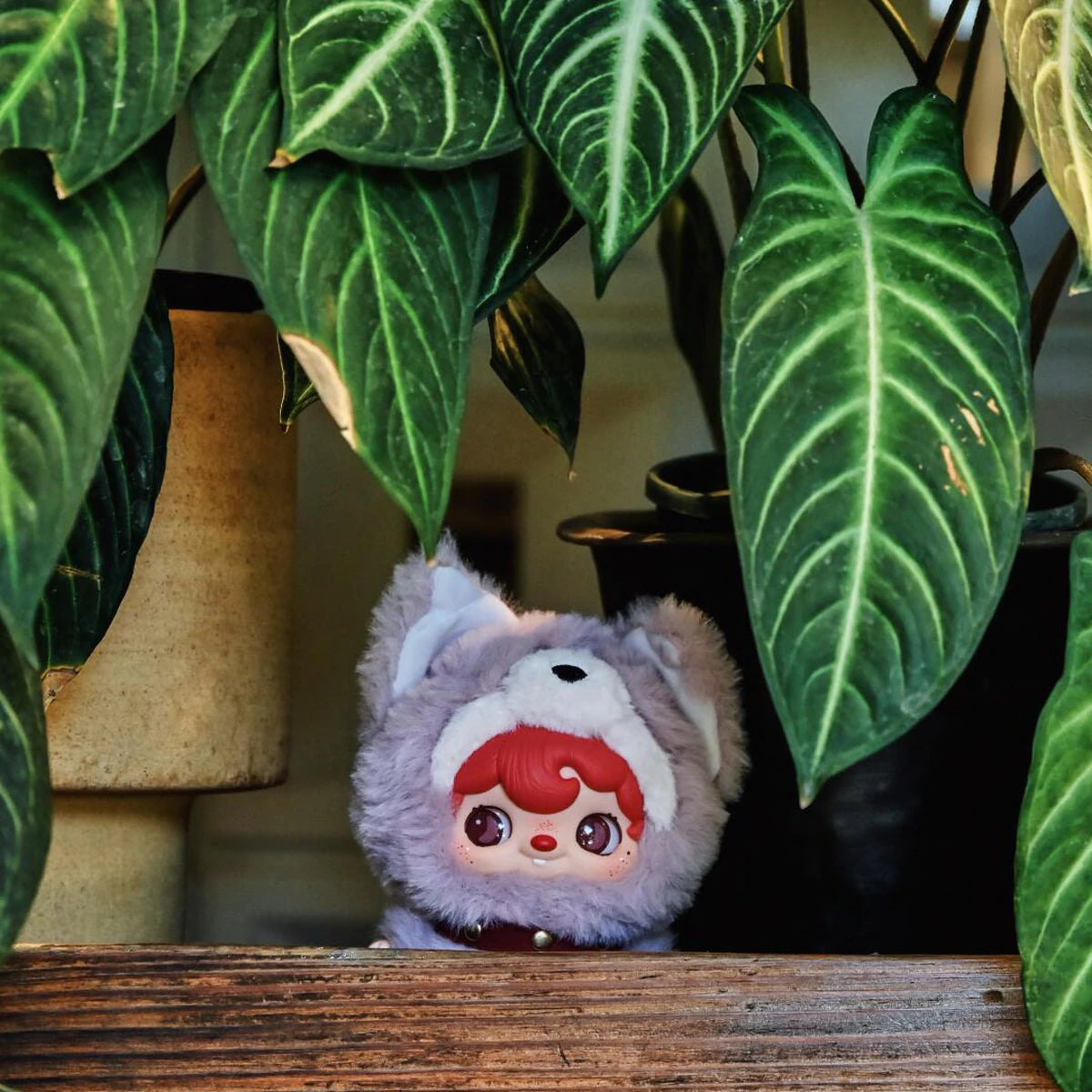 POUKAPOUKA in a lavender Tom costume peeking from beneath large green leaves