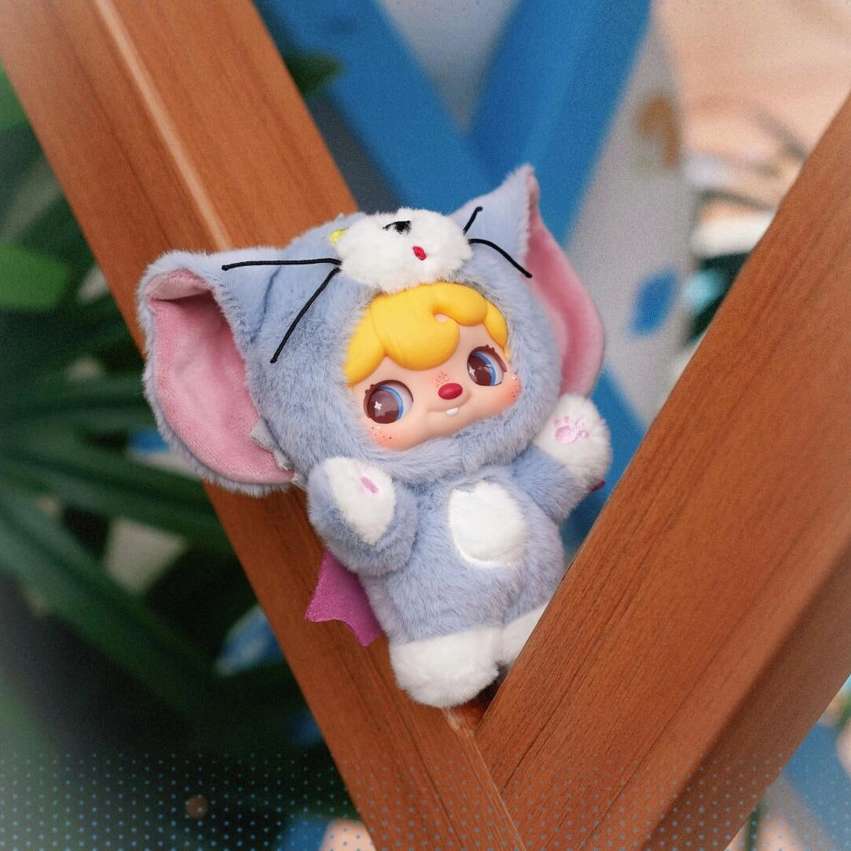 POUKAPOUKA in a gray Tom costume wedged playfully between wooden rails