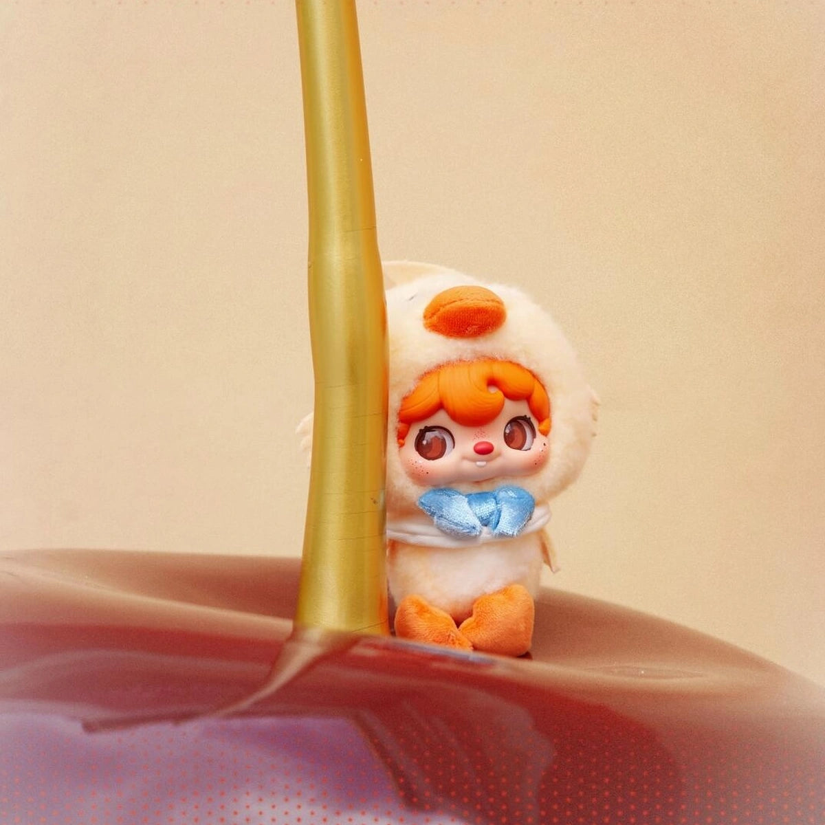 POUKAPOUKA in a Quacker duck costume peeking around a gold pole