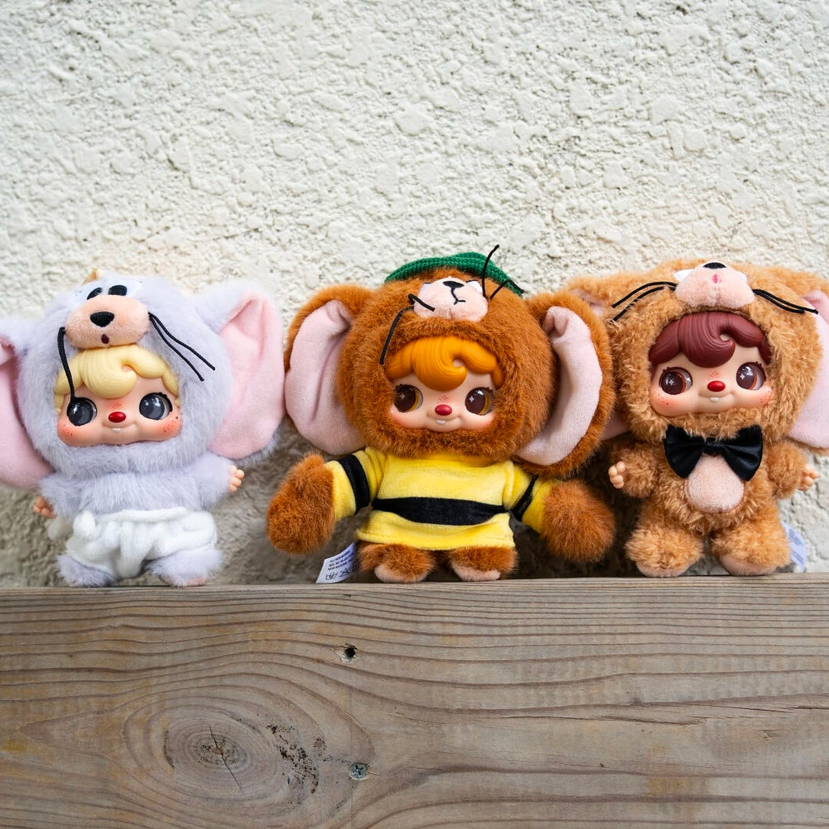 Four POUKAPOUKA Tom and Jerry costume plush designs lined on a wooden ledge