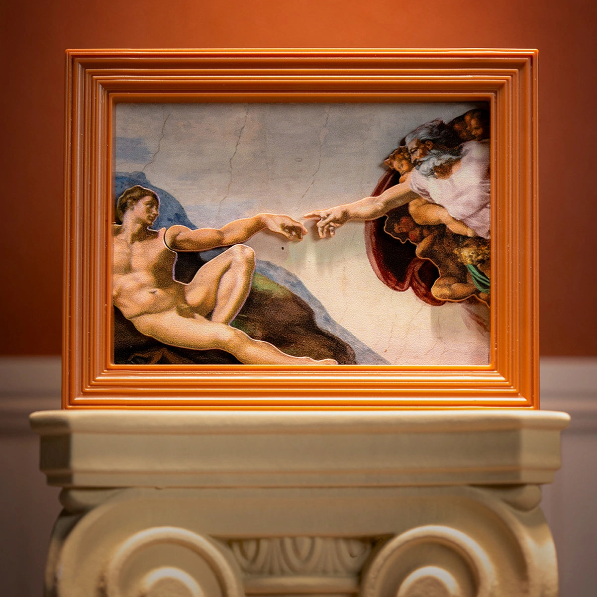 The Creation of Adam touching hands in orange frame on an Ionic column, QueSera Living Paintings