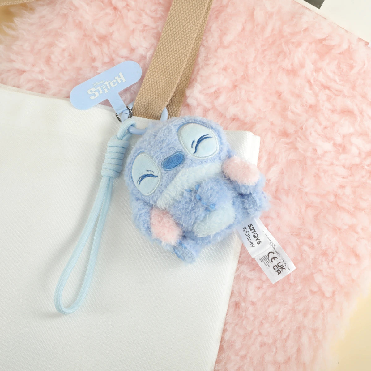 Smiling Stitch plush phone charm attached to a white bag by its blue wrist strap