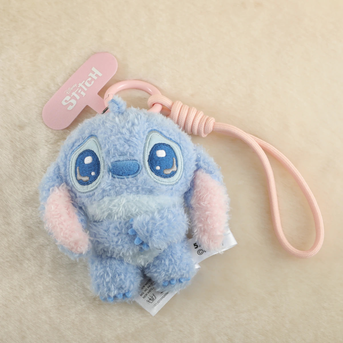 Teary-eyed Stitch plush phone charm with folded hands and pink wrist strap