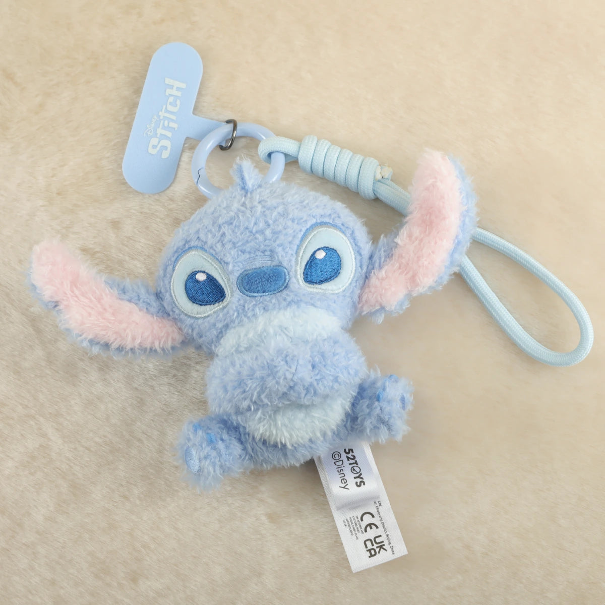 Relaxed Stitch plush phone charm sitting with arms spread and blue wrist strap