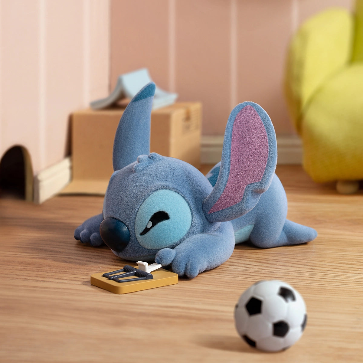 Stitch lying on a floor after pressing a rectangular switch beside a soccer ball