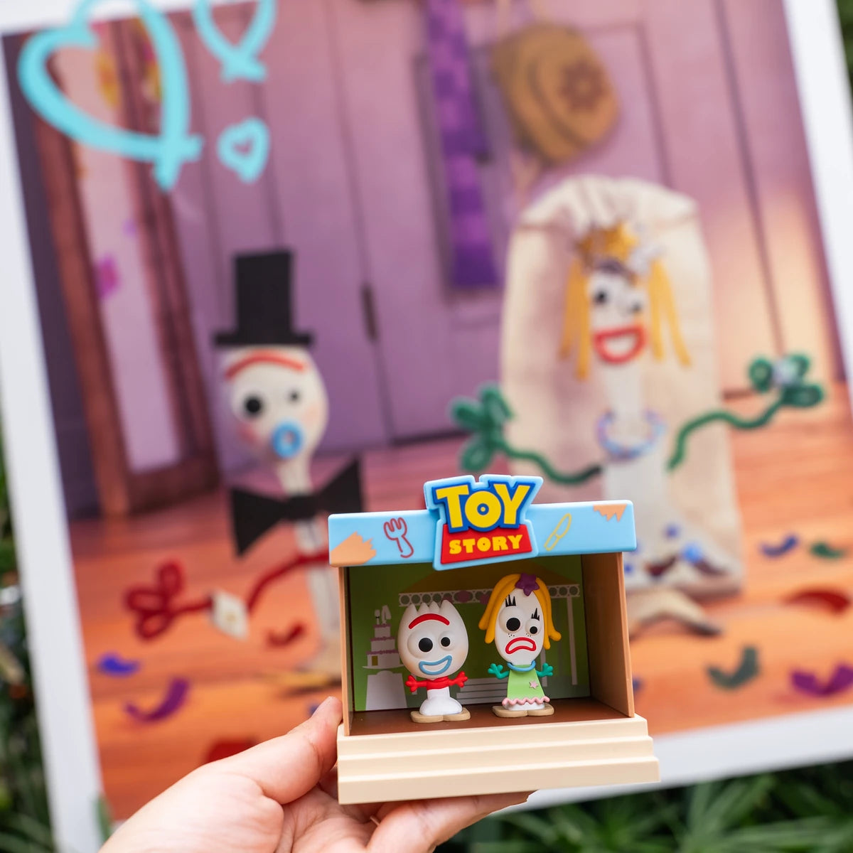 Forky and Karen Beverly stage figure held in front of a colorful craft mural